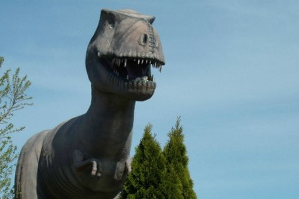 A Tyrannosaurus stands over the remains of an abandoned mini-golf course.