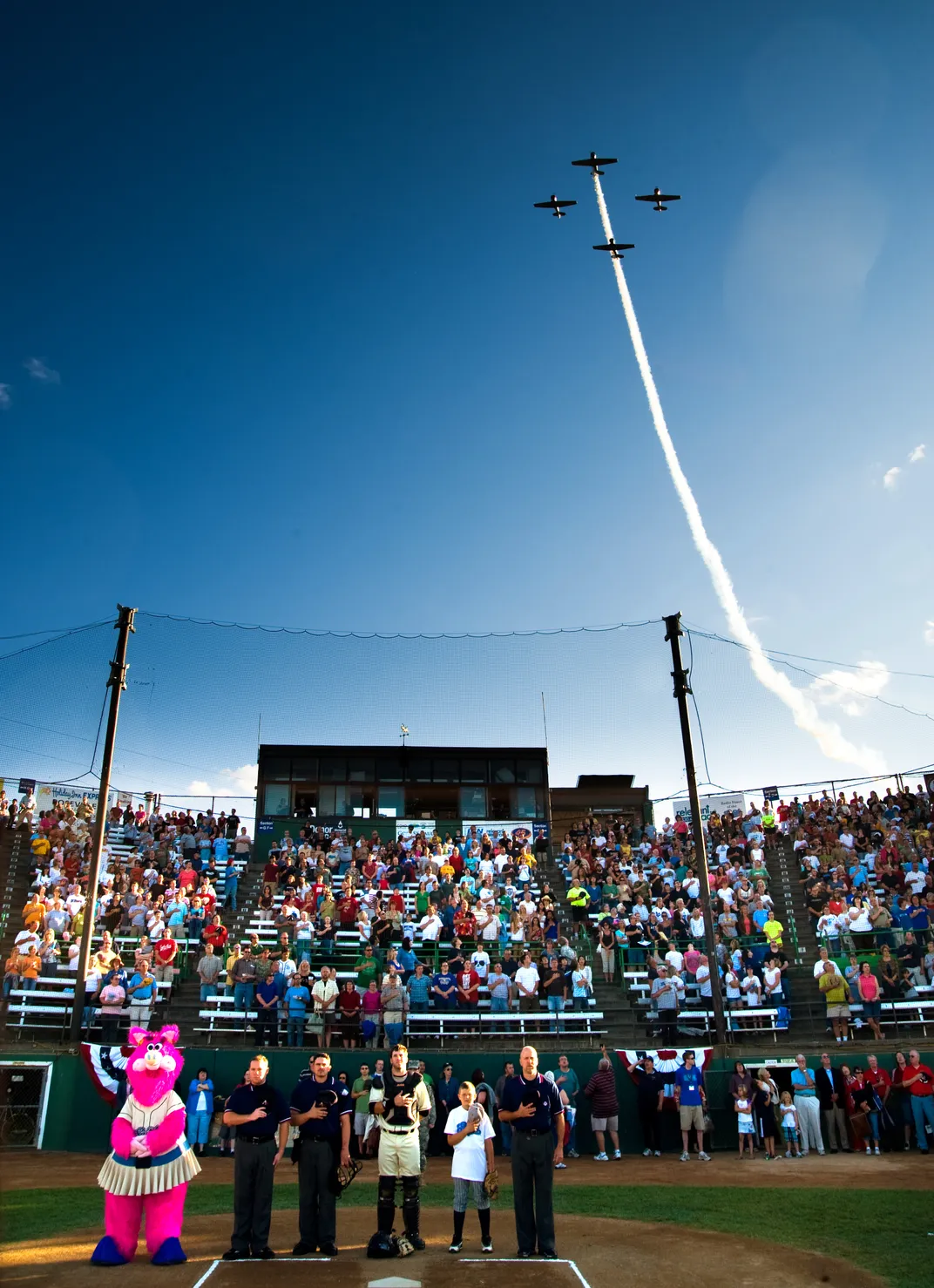 people stand for the national anthem at a baseball game