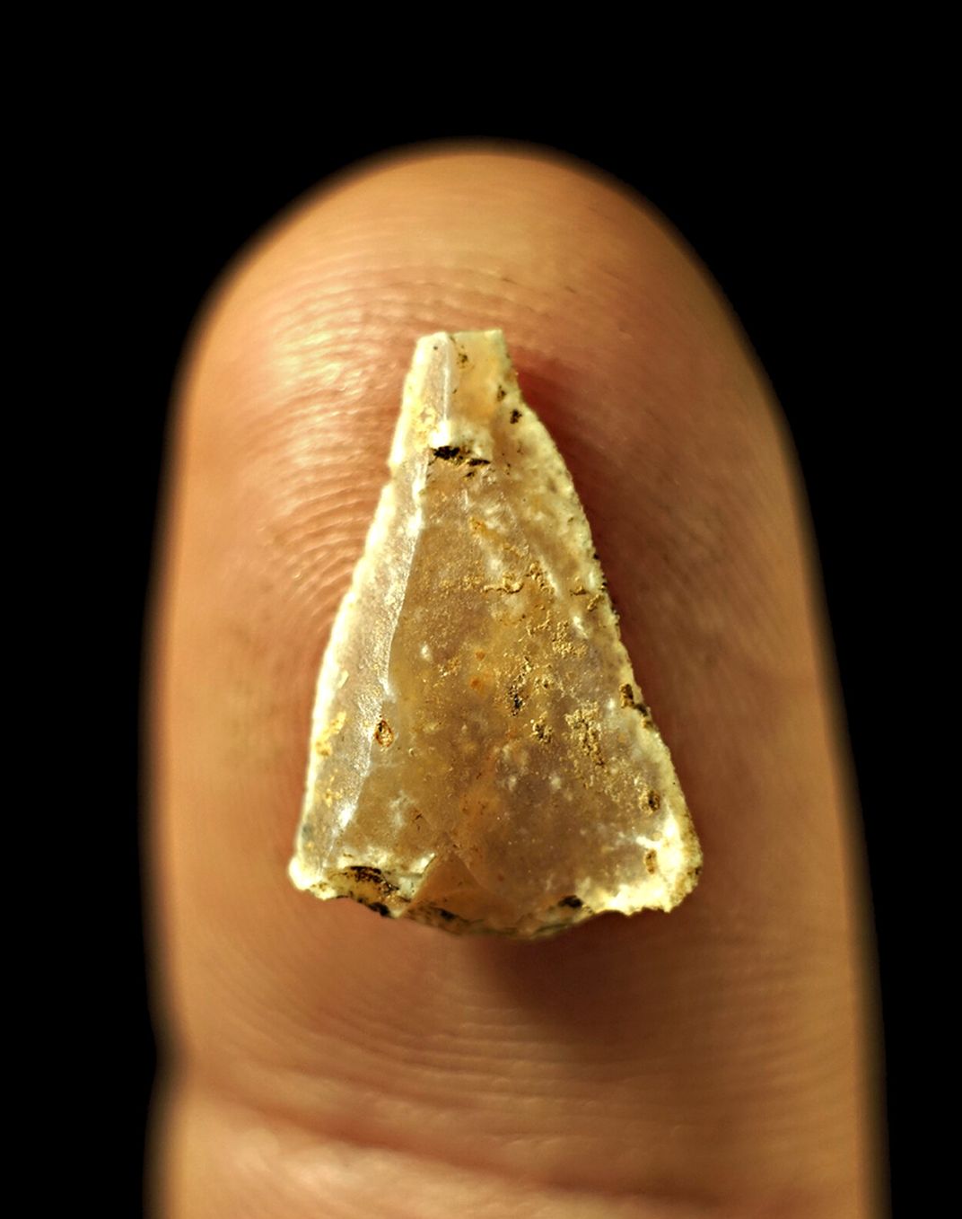 Tiny triangular piece of stone on fingertip