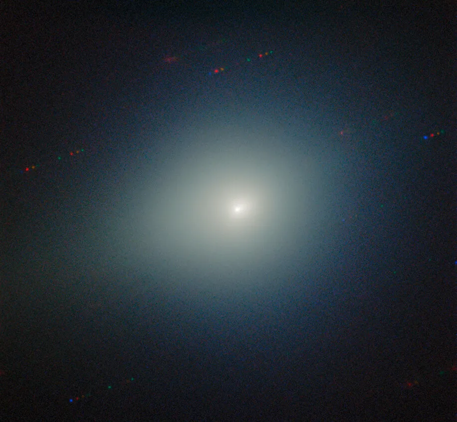 A comet glows in white-yellow at the center. A few streaks of differently colored dots appear in the background