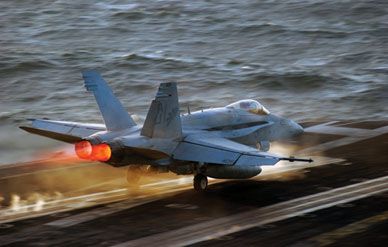An F/A-18 Hornet lights its afterburners to leap from the deck of the aircraft carrier USS Theodore Roosevelt.