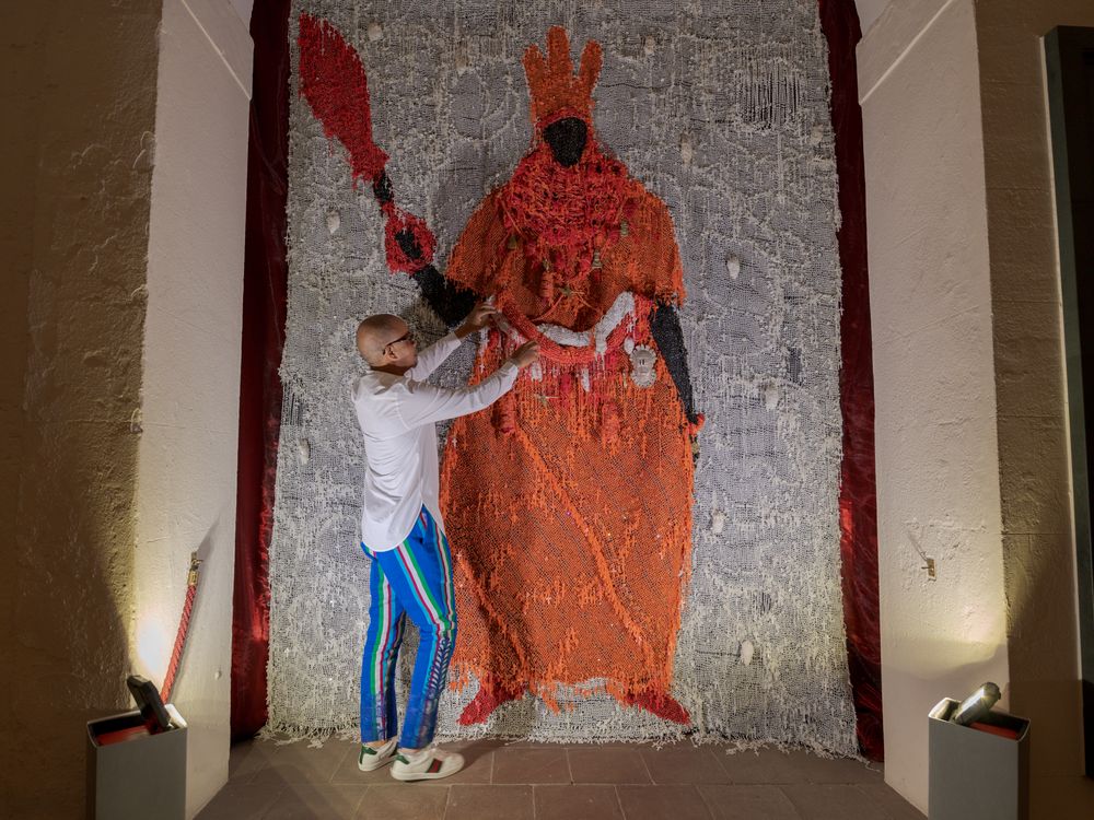 Artist posting with work of man dressed in orange garb