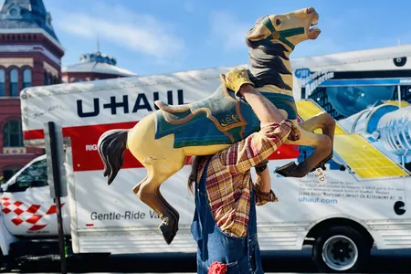 A Smithsonian staffer carries a horse from the carousel for transport to the restoration facility.