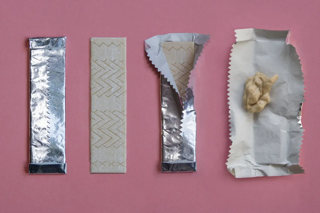 An image of a stick of gum shown in the stages of being used. Starting with unwrapping the stick of gum to ending with sticking the used piece in its foil wrapper. The sequence is shown against a pink background.