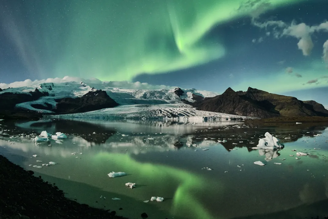 A reflection of the aurora borealis illuminates the icy waters