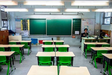 In this photo taken on March 6, 2020, primary school teacher Billy Yeung records a video lesson for his students, who have had their classes suspended due to coronavirus, in his empty classroom in Hong Kong.