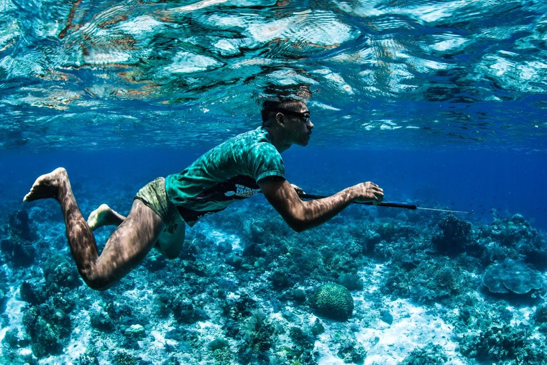 Man swimming underwater with spear