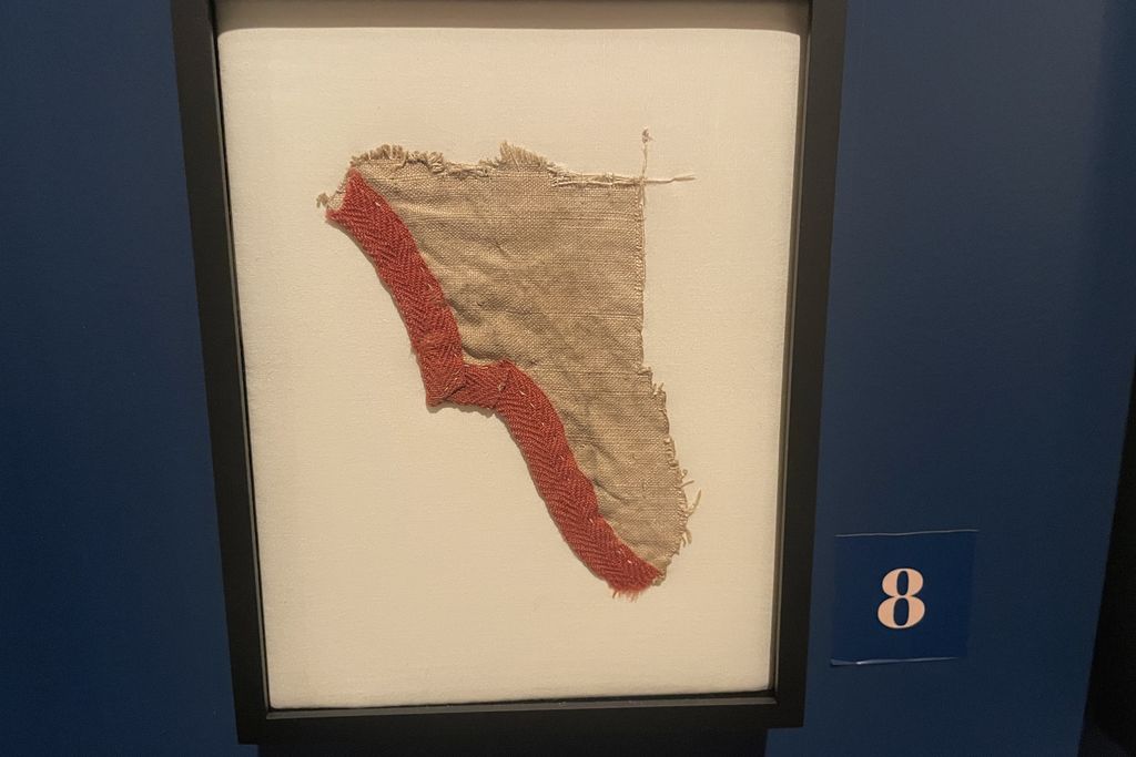 Scrap of old fabric in a frame hanging on a dark blue wall