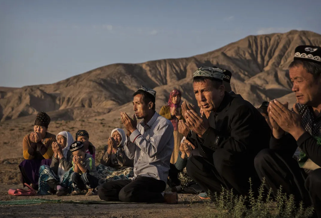 A Uyghur family in Xinjiang prays at the grave of a loved one on September 12, 2016, the morning of the Corban Festival.