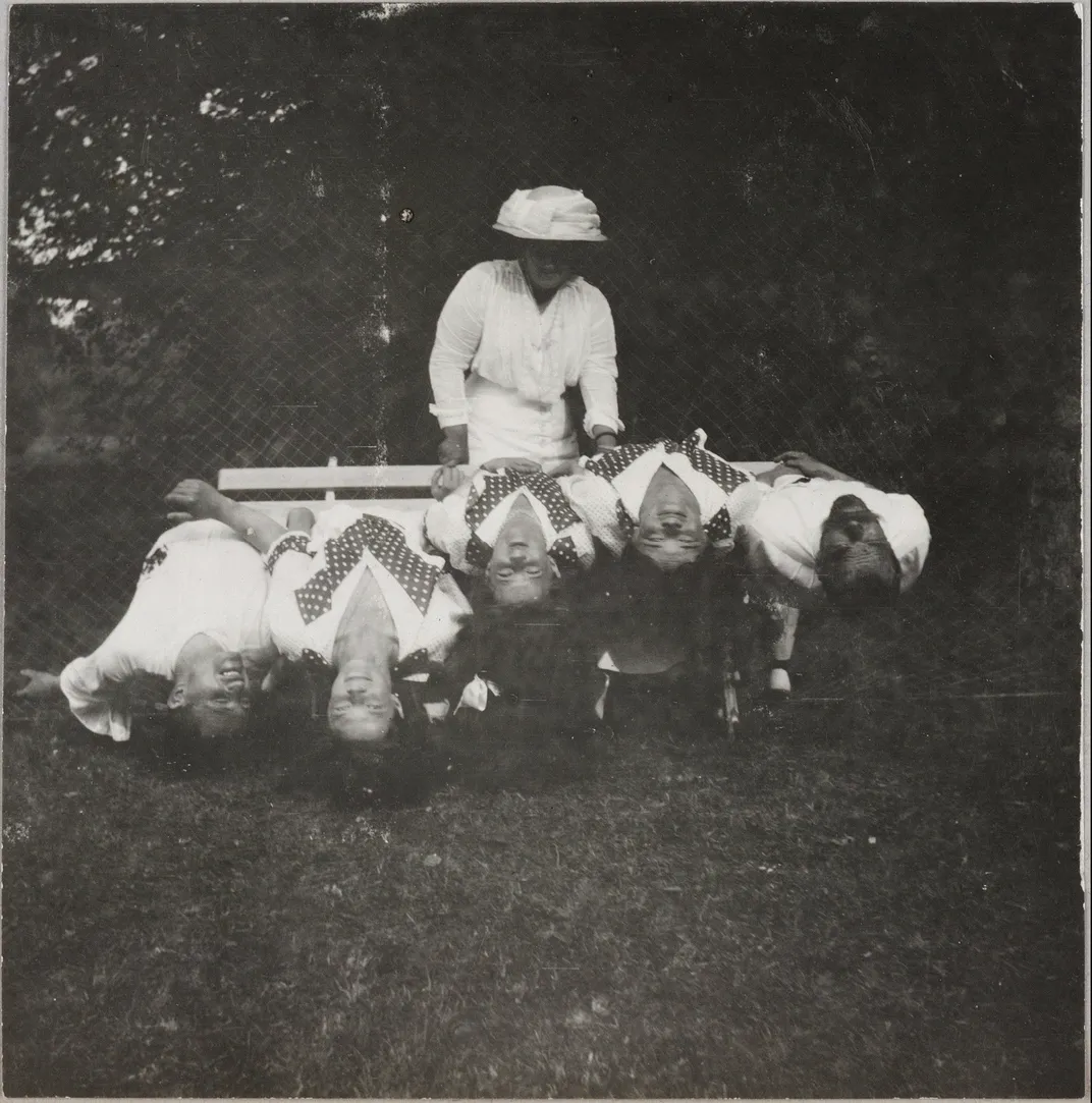 Three of the Romanov sisters goof around on a bench with their father and a favorite officer.