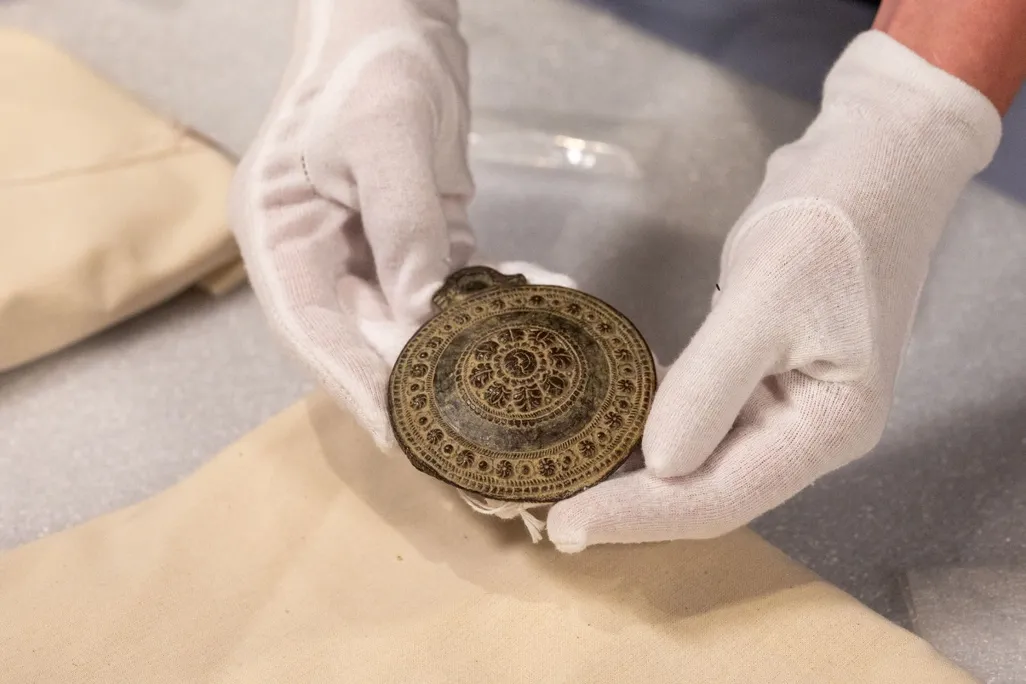 Gloved hands holding a medallion