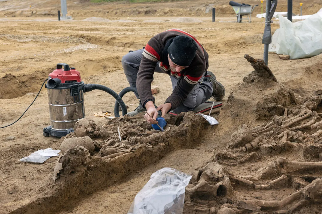 Archaeologist bent over bones at dig site