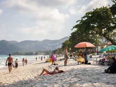 Tourists sunbathe on Chaweng Beach on Koh Samui&#39;s eastern coast.