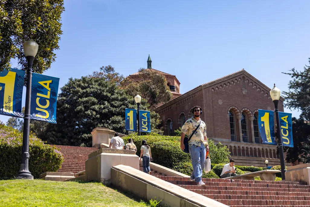 A photo of a college campus with a male student walking down some stairs