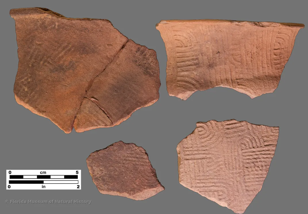 a broken piece of an ancient pot with marks stamped into it