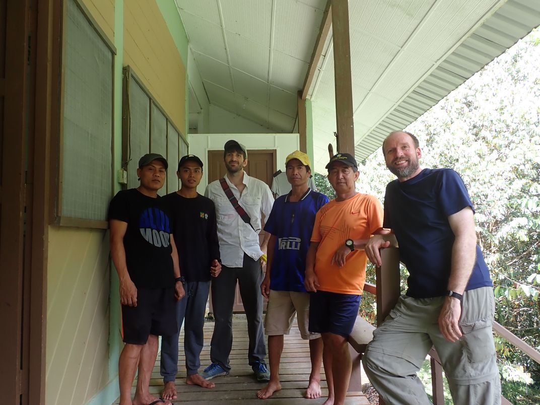 Jacob Saucier and Christopher Milensky pose with local guides on a porch in Borneo. 