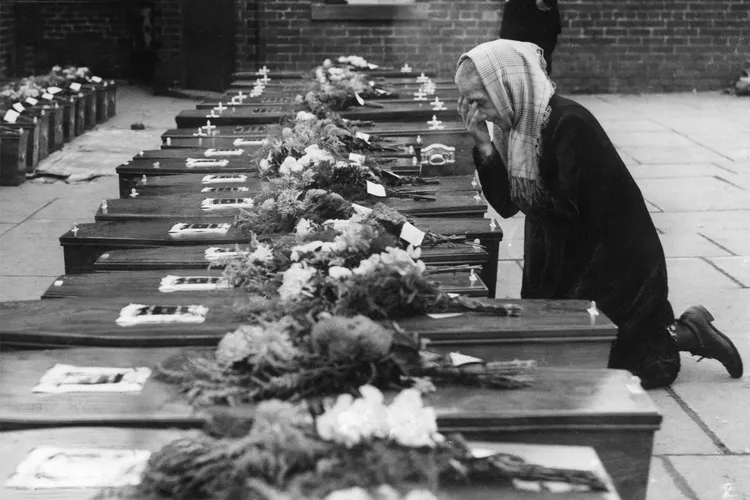 A woman kneels in prayer in front of children's coffins in Freckleton, England.