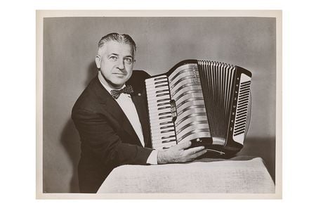 Photograph of John Vassos holding the Marchesa model accordion he designed for M. Hohner, 195-? / unidentified photographer. John Vassos papers, 1915-1989. Archives of American Art, Smithsonian Institution.