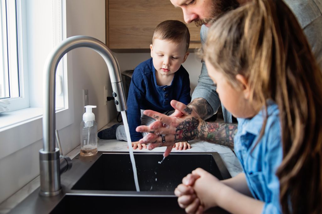 father teaching children how to wash their hands