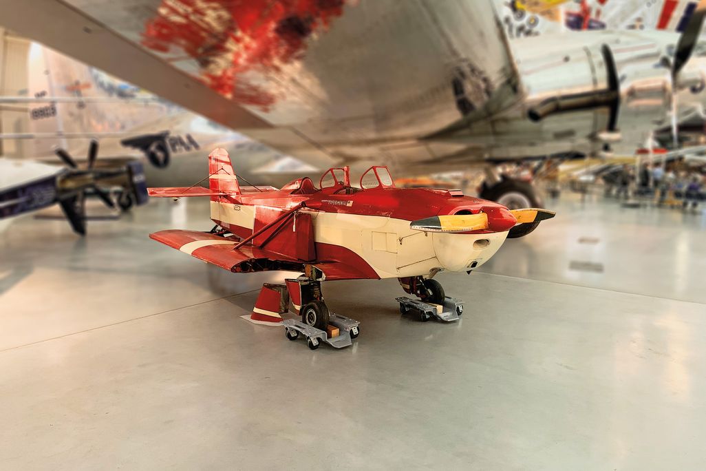 a red vintage airplane sits in an hanger