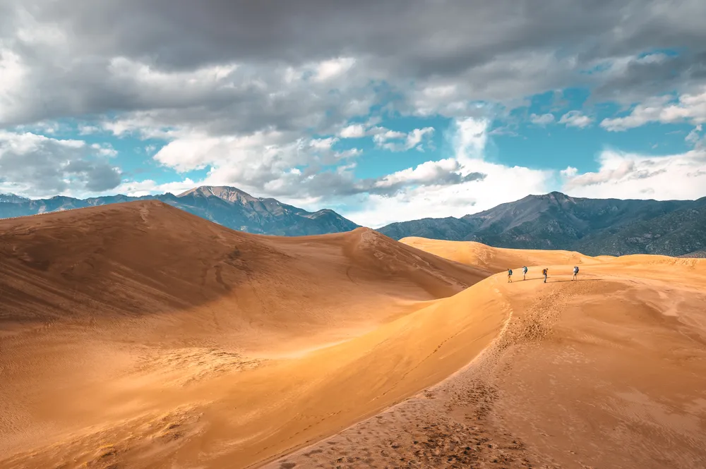 一群背包客站在巨大的沙丘之间。