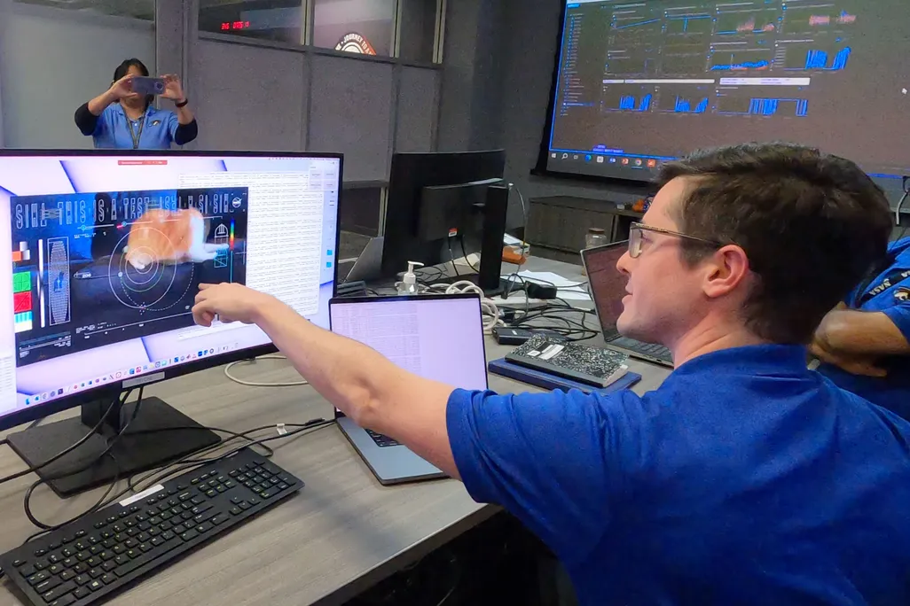 man points to a computer screen with a cat on it