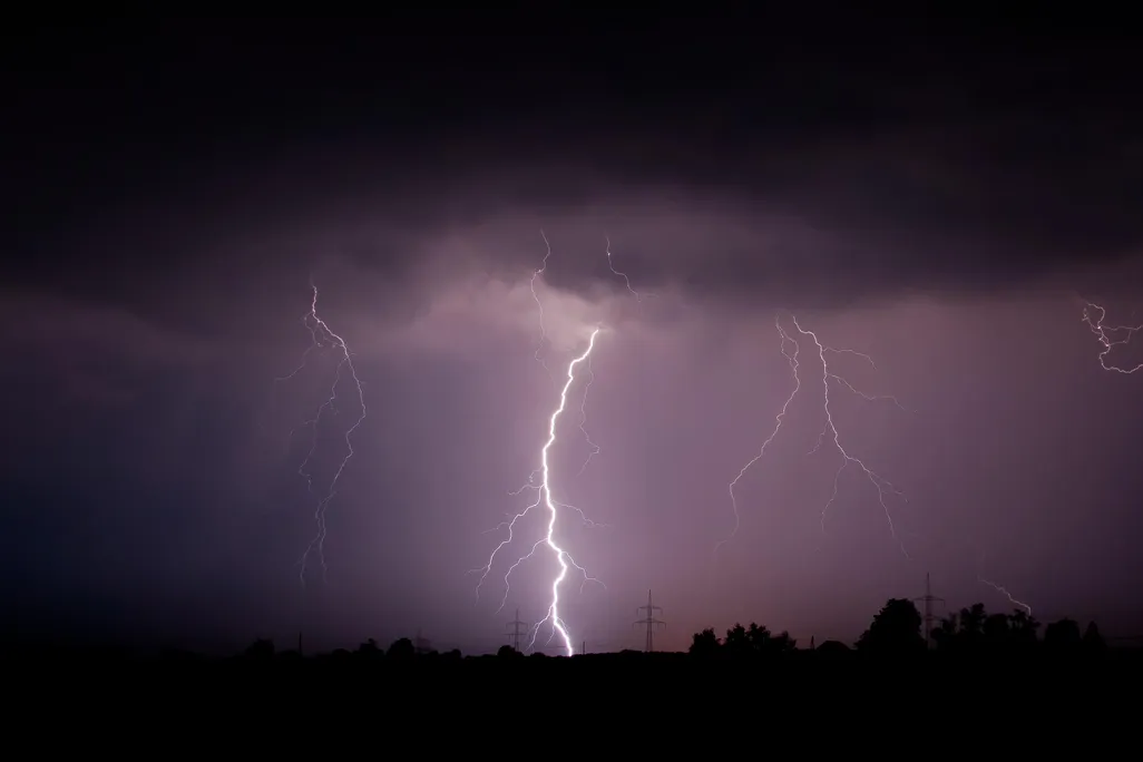 A photo of lightning striking the ground against a moody purple sky