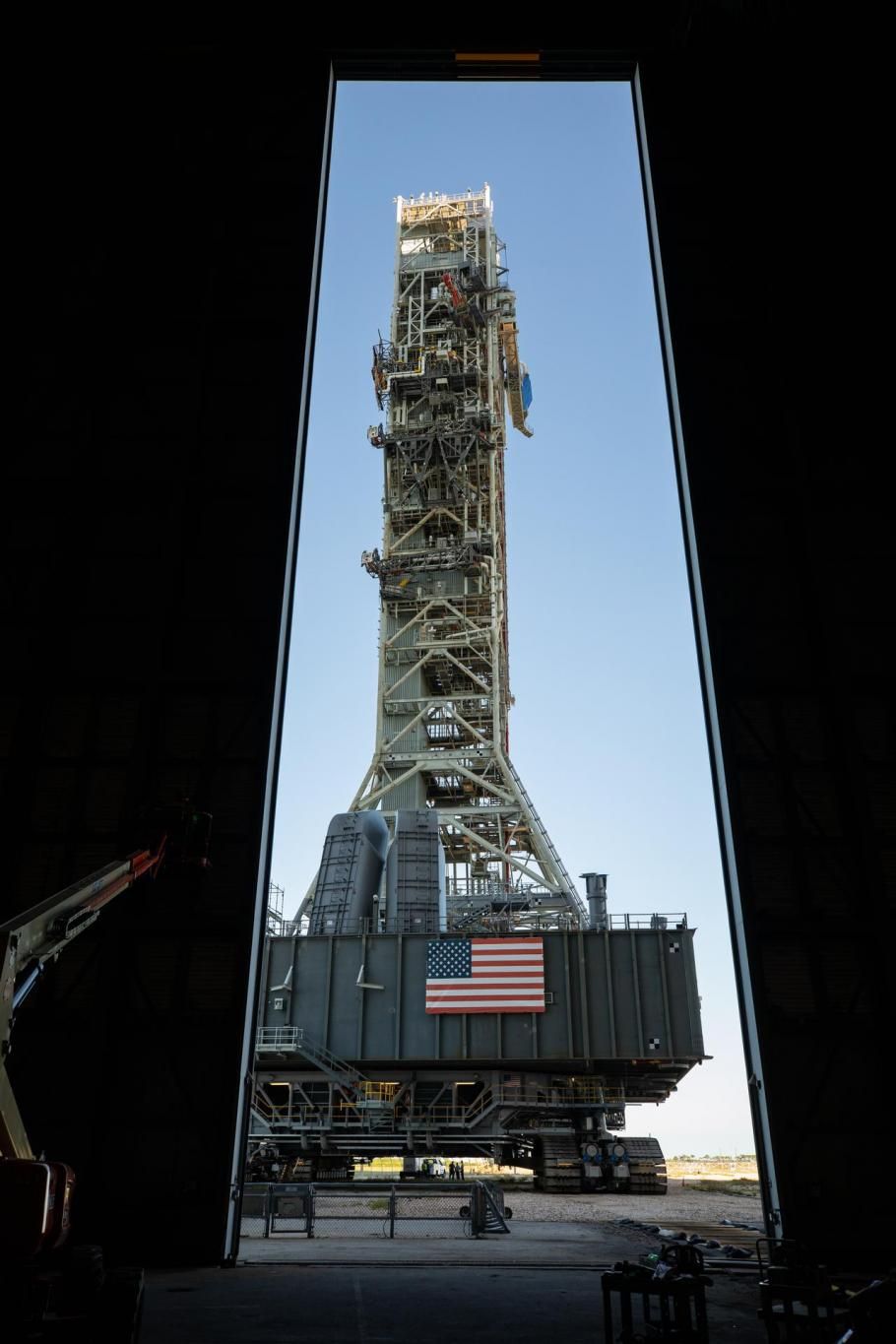 A mobile launcher seen through doors. An American flag is displayed beneath it.