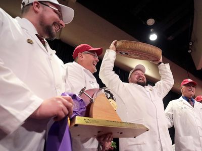 Christian Schmutz of the Swiss Cheesemakers Association hoists a 77-pound wheel of gruyère, which won the World Championship Cheese Contest last week.