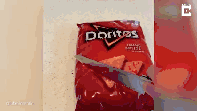 Gif of someone cutting into a bag of Doritos that is actually a cake