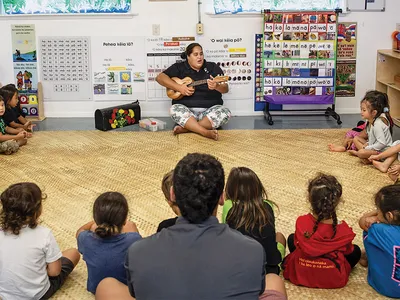 Nāoli Weller, a nursery school teacher at Nāwahī, leads her class in traditional songs. In the room hang signs that help pupils master the Hawaiian language.