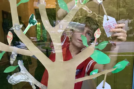 A boy adds a wish for the health of delivery workers during the 2020 pandemic. This  paper wish tree is inspired by artist Yoko Ono’s Wish Tree for Washington, on view at the Hirshhorn Museum’s Sculpture Garden.