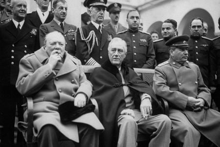 Fleet Adm. William D. Leahy stands directly behind President Franklin D. Roosevelt, who is seated between Winston Churchill (left) and Joseph Stalin (right), at the Yalta Conference during World War II.