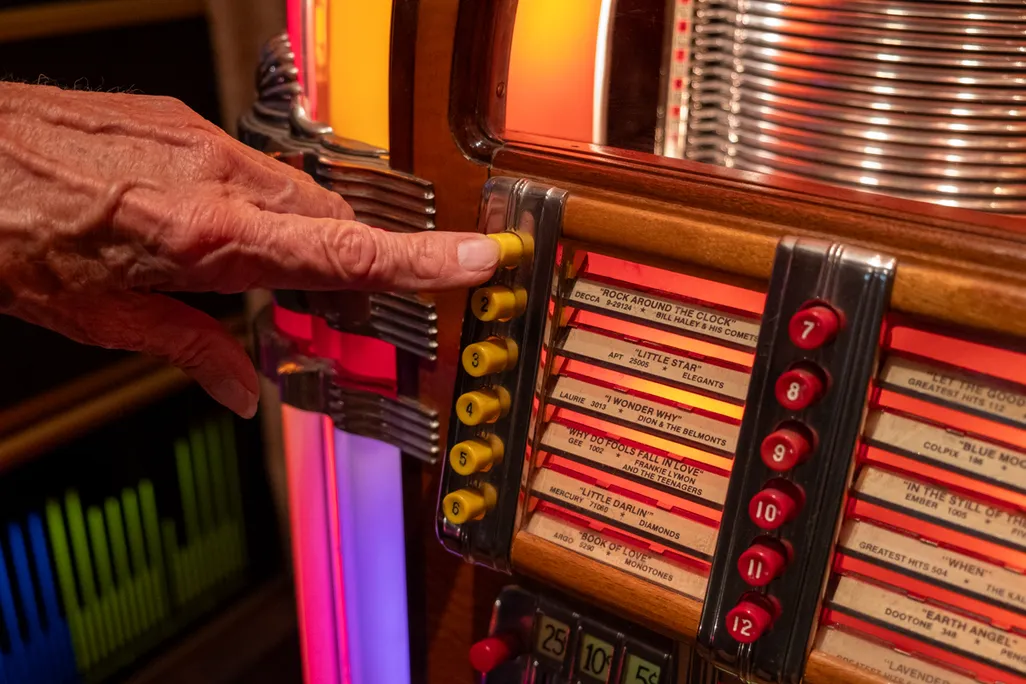 A listener selects “Rock Around the Clock” by Bill Haley & His Comets on a classic Wurlitzer “bubbler.”