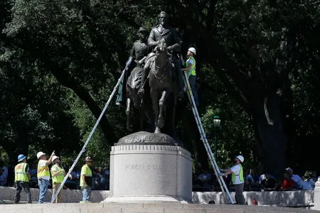 Workers inspect a statue of Robert E. Lee in a public park in Dallas, Wednesday, Sept. 6, 2017.