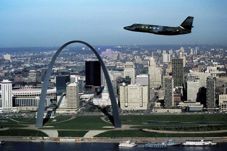 An air-to-air left side view of a C-140 Jetstar aircraft of the 1866th Facility Checking Squadron, Scott Air Force Base, Illinois, flying by the St. Louis Arch.