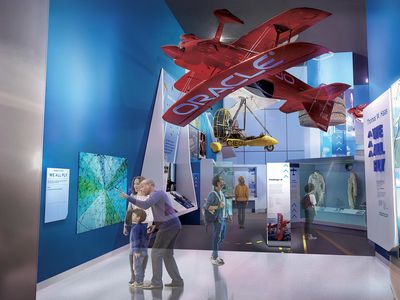museumgoers under a red Oracle aircraft
