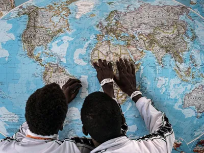 Gambian asylum seekers look at a map while waiting in an Italian migrant center. 