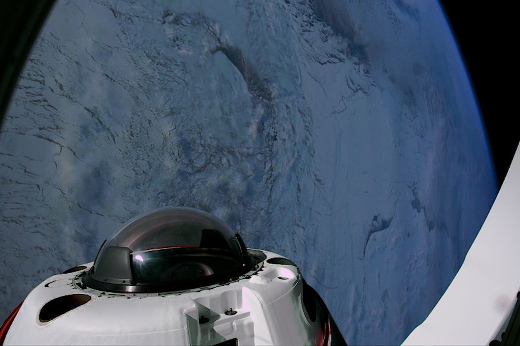view looking down at polar ice from space out the window of a spacecraft, with a cupola on the craft visible in the foreground