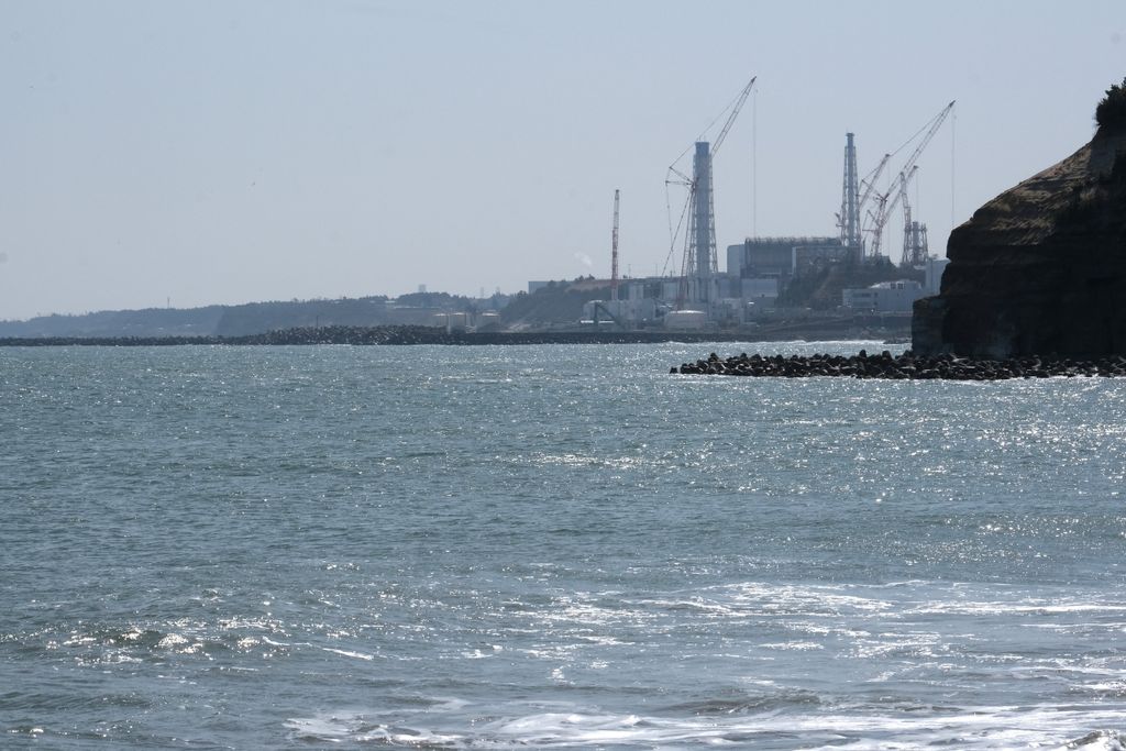 A photo shows the Fukushima Daiichi nuclear power plant on the horizon, across the sea