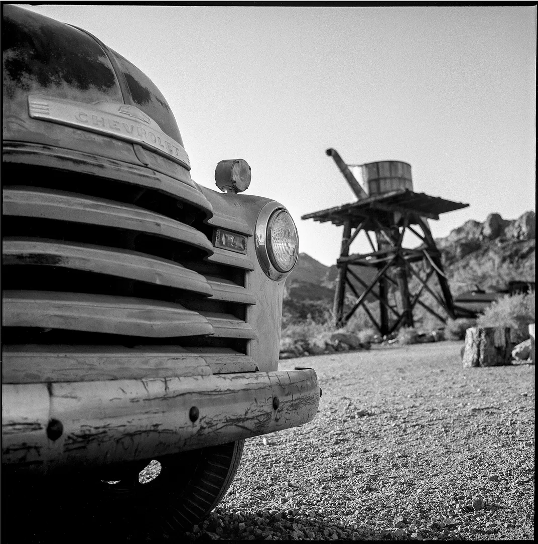 11 - An old Chevy truck is parked close to a water tank in a Southwestern ghost town.