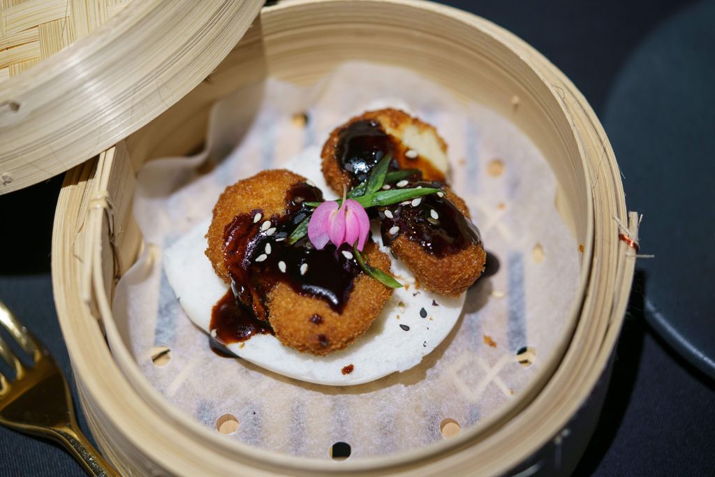 Chicken nuggets made from lab-grown meat covered with a sauce and flower garnish.