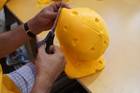 A guest trims the excess foam off a baseball cap.