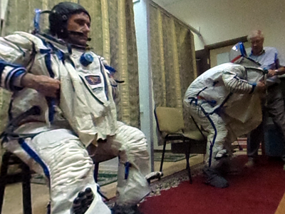 Yuri Malenchenko (left) and Tim Kopra are helped out of their spacesuits after a rehearsal.