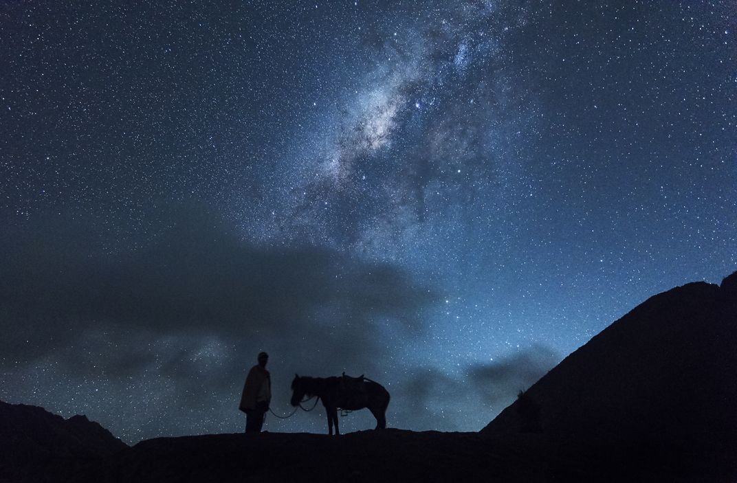 A man and his horse underneath the night sky