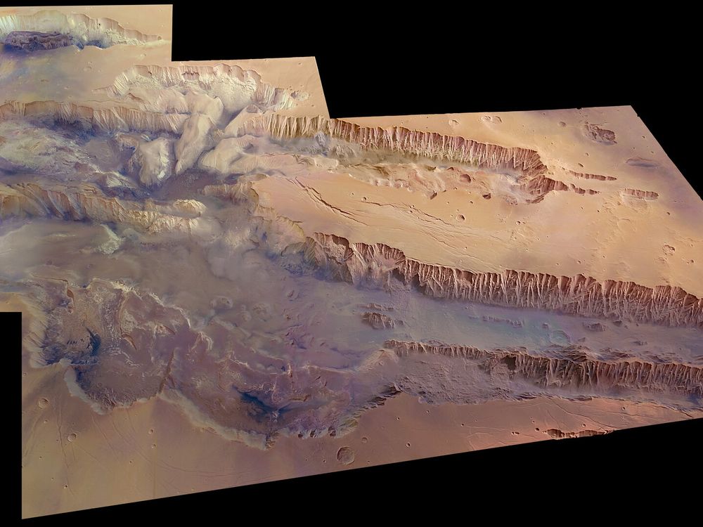 An image of the Valles Marineris on planet Mars. The region is as large as the United States and the biggest canyon in the Solar System. The region looks red and arid.