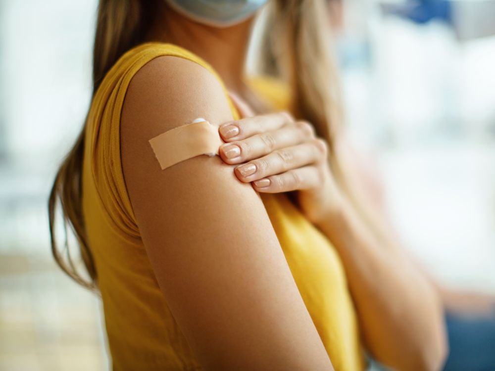 A young woman with a bandaid on her arm after getting a covid vaccine