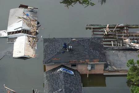 People sit on a roof waiting to be rescued after Hurricane Katrina