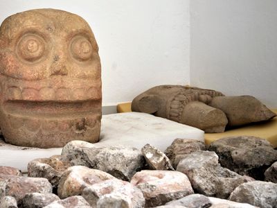 In this 2018 photo provided by Mexico's National Institute of Anthropology and History, INAH, a skull-like stone carving and a stone trunk depicting the Flayed Lord, a pre-Hispanic fertility god depicted as a skinned human corpse, are stored after being excavated from the Ndachjian–Tehuacan archaeological site in Tehuacan, Puebla state, where archaeologists have discovered the first temple dedicated to the deity. 