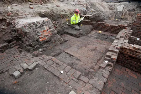 An archaeologist studies remains of the Curtain theater's foundations.